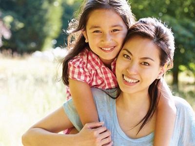 Young girl smiling and hugging her mother after seeing a special needs dentist in Fort Worth, Texas